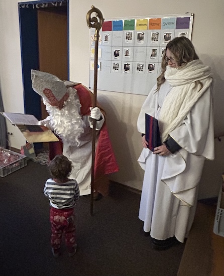 Bild 1: Der Nikolaus las jedem Kind ein paar persönliche Worte aus dem goldenen Buch vor, bevor die Engel ein Geschenk vom Wunschzettel überreichten. (Foto: Malteser)